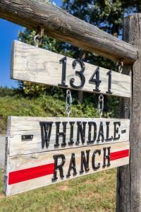 un cartel de madera en un poste de madera con un rancho junto al viento en Farm living at it's best!, 
