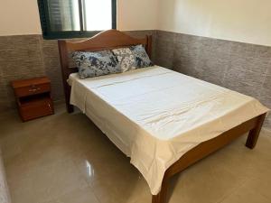a bed with a wooden headboard and a night stand at YUPOP APARTAMENTO in São Tomé