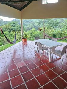 a patio with a table and chairs and a hammock at Cabaña Mountain Ocean View Minca in Minca
