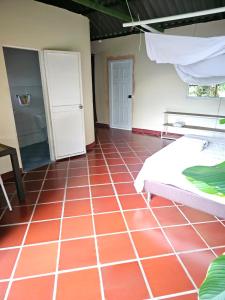 a room with a bed and a red tiled floor at Cabaña Mountain Ocean View Minca in Minca