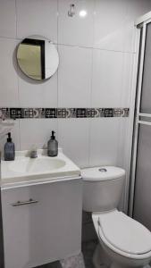 uma casa de banho branca com um WC e um espelho. em Práctico aparta estudio Envigado 301 em Envigado