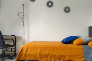 um quarto com uma cama com um cobertor laranja e uma secretária em Práctico aparta estudio Envigado 301 em Envigado