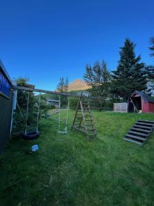 un parque infantil con un columpio en un patio en Room W/hottub, sauna and firepit, en Seyðisfjörður