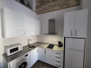 a white kitchen with a sink and a microwave at Apartamento El Arrumbador in Jerez de la Frontera