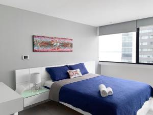 ein Schlafzimmer mit einem blauen Bett und einem Fenster in der Unterkunft Penthouse de 2 habitaciones con vista al rio y parking in Guayaquil