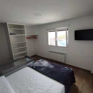 1 dormitorio con 1 cama y TV. en Razo , Costa da Morte, en A Coruña
