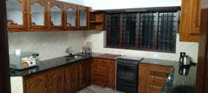 a kitchen with wooden cabinets and a black dishwasher at Holiday homes in kidangoor kottayam kerala in Kottayam