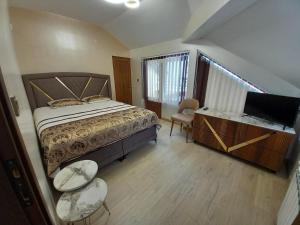 a bedroom with a bed and a tv and a desk at ЕЛЕГАНС къща за гости in Dospat
