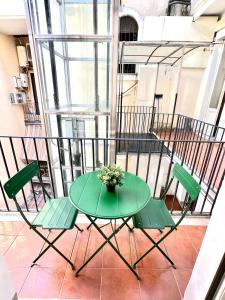 un tavolo verde e sedie sul balcone di Trevi Romantic Alcova a Roma