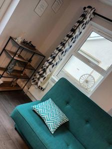 uma sala de estar com um sofá verde e uma janela em Tummock Studio perfect for exploring the North coast em Kilraghts