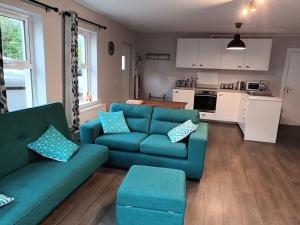 uma sala de estar com um sofá azul e uma cozinha em Tummock Studio perfect for exploring the North coast em Kilraghts