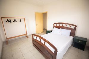 1 dormitorio con cama de madera con sábanas blancas en Apartamento Vista Mar, en São Tomé