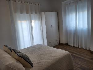 1 dormitorio con 1 cama con cortinas blancas y armario en Apartamento La Albariza, en Jerez de la Frontera
