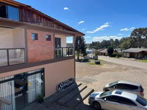two cars parked in front of a building at Pousada Serra Geral in Cambará