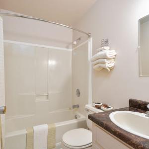 Baño blanco con aseo y lavamanos en Kelly's View Motel, en Boularderie East