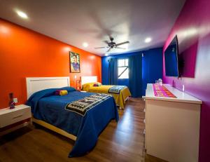 2 łóżka w pokoju pomarańczowym i niebieskim w obiekcie Hotel Cantaritos w mieście Rosarito