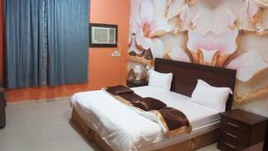 a bedroom with a bed with a painting on the wall at شقق الخيول البرونزية للشقق المخدومة in Şabyā