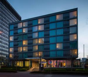 ein großes Bürogebäude aus Glas mit eingeschaltetem Licht in der Unterkunft DoubleTree by Hilton Frankfurt Niederrad in Frankfurt am Main