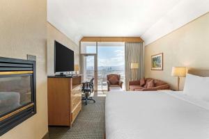 Best Western Plus Kelowna Hotel & Suites في كيلونا: غرفة فندقية بسرير وتلفزيون بشاشة مسطحة