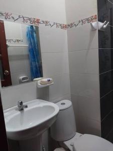 y baño con lavabo, aseo y espejo. en D-201, en Moyobamba