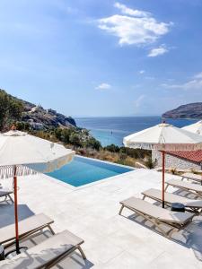una piscina con sedie, ombrelloni e oceano di Eleonas Limeni a Limeni