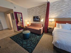a hotel room with a bed and a couch and a mirror at Home2 Suites By Hilton Allentown Bethlehem Airport in Bethlehem