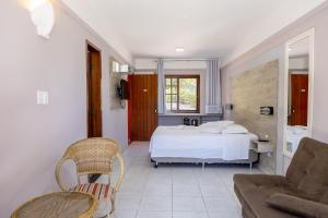 um quarto com uma cama, uma cadeira e um sofá em Saint Germain - Lagoa da Conceição em Florianópolis