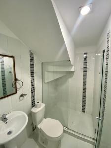 a white bathroom with a toilet and a sink at Hotel Estefanía Princess 84 in Barranquilla