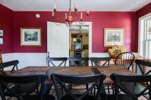 een eetkamer met rode muren en een tafel en stoelen bij 1820 House - VT Charm + Modern Comforts + Hot Tub in Stowe