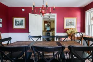 a dining room with red walls and a table and chairs at 1820 House - VT Charm + Modern Comforts + Hot Tub in Stowe