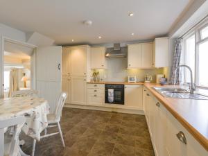 a kitchen with white cabinets and a table and a dining room at Prydes Cottage in Saint Mawes