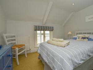 a bedroom with a bed and a chair and a window at Prydes Cottage in Saint Mawes