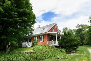 a red brick house with a gambrel roof at 1820 House - VT Charm + Modern Comforts + Hot Tub in Stowe