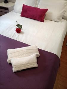 Bett mit weißer Bettwäsche, roten Kissen und Handtüchern in der Unterkunft Apartamento Esperanza in Sevilla
