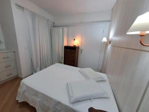 Apartamento no Centro de Brusque/SC في بروسك: غرفة نوم صغيرة مع سرير أبيض وخزانة