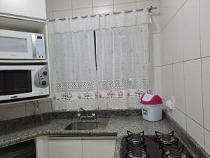 a kitchen with a stove and a sink and a microwave at Apartamento no Centro de Brusque/SC in Brusque