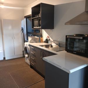 a kitchen with a washer and a sink and a microwave at Tiwai Waka Retreat in Wellington