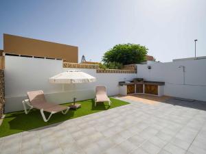 un patio con due sedie e un ombrellone di Mahostly Casa Fika a Corralejo