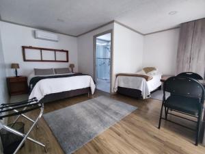 a bedroom with two beds and a chair in it at Casa Hotel Trocha Angosta in Constitución