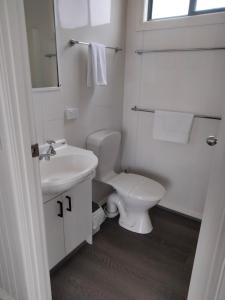 a white bathroom with a toilet and a sink at Lang Lang Caravan Park 