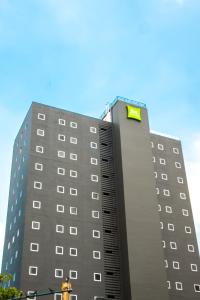 a tall building with a yellow sign on it at Ibis Styles El Malecon Guayaquil in Guayaquil