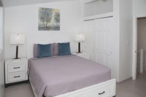 a white bedroom with a bed and two lamps at 232C South Finger in Jolly Harbour