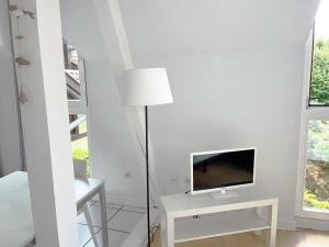 uma sala de estar branca com uma televisão e um candeeiro em LES MARAICHERS em Estrasburgo