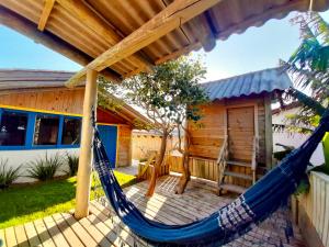 a hammock on a deck in front of a house at Pousada Villa Del Mar in Farol de Santa Marta