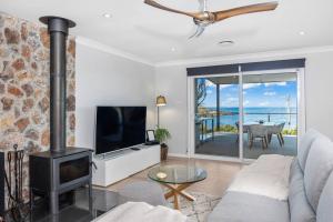 a living room with a fireplace and a tv at O'Hara, Waterfront Merry Beach in Kioloa