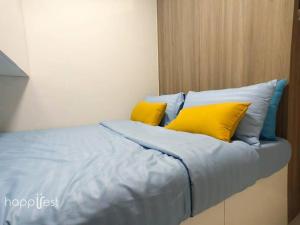 a bed with yellow and blue pillows on it at Happirest at Coast Residences, Pasay - 1 Bedroom with Balcony in Manila