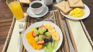 a table with two plates of breakfast food and a cup of coffee at Valicha Casa Hotel in Cusco