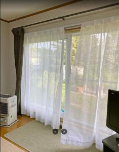 a window with white curtains in a room at FURANO UEDA HOUSE in Furano