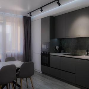 a kitchen with black cabinets and a table and chairs at CityView Apartment in Chişinău