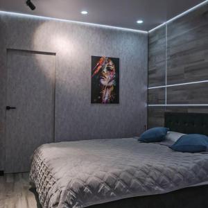 a bedroom with a bed with a painting on the wall at CityView Apartment in Chişinău
